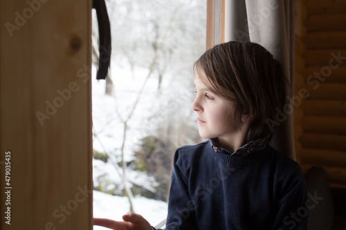 Beautiful preteen child in a little fancy wooden cottage, looking out of the window photo