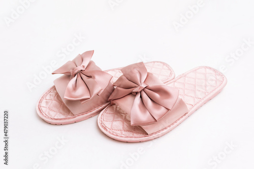 Close-up of pink satin female glamorous stylish home slippers with bows isolated on a white background  © Марина Демешко