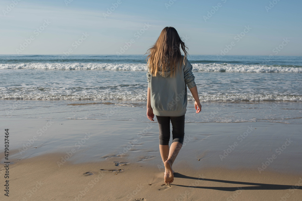 Beautiful young girl walking quietly on the sunny beach