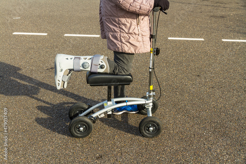 Woman with leg and foot  in surgical boot using a knee scooter walker landscape. photo