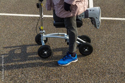 Woman with leg and foot  in surgical boot using a knee scooter walker.