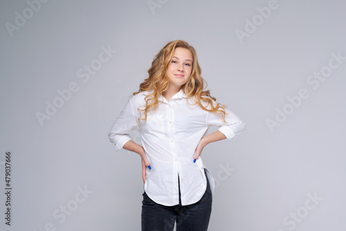 Smiling young blonde woman in white shirt posing isolated on gray walls background studio portrait with facial expressions. People lifestyle concept. Copy space for copy.