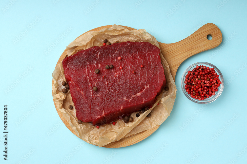 Obraz premium Concept of cooking with raw beef steak on blue background