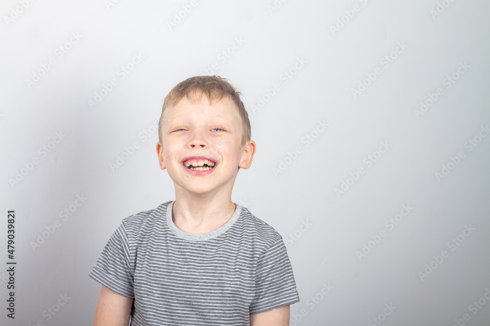 Caucasian boy 7 years old laughs and has fun on a gray background in the studio Caucasian boy 7 years old laughs and has fun on a gray background in the studio