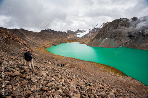 Female trekker backpacker hiking at bank of Beautiful landscape of turquoise Ala-Kul Lake, Karakol valley, Issyk-kul region, Ala-kul lake Terskey Alatau mountain range, Kyrgyzstan, Central Asia photo