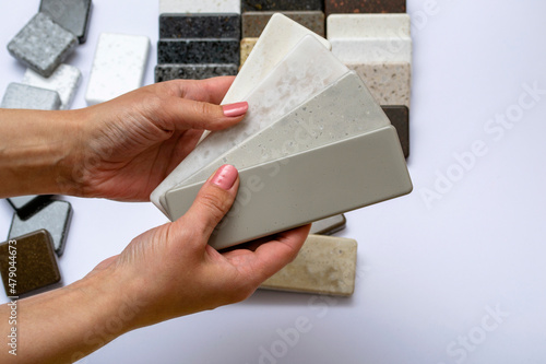 Mock up from natural stones, top view, closeup. Female hands advertises repair materials. Floor tiles, tiles, countertops.