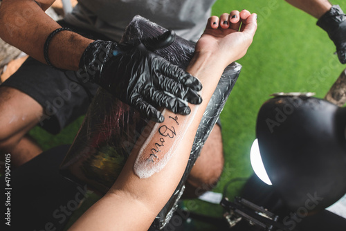 Canvas Print A tattooist cleans a fresh name tattoo on a client's forearm with gentle soap