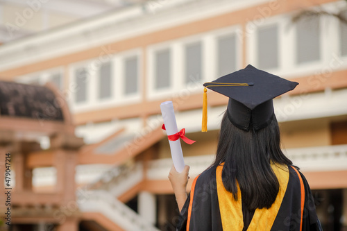 Graduates raise their hands to celebrate graduation with diplomas and pride and happiness.