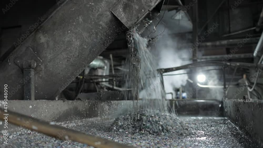 Recycling plastic by dissolving in a metal container using hot steam. A large amount of crushed plastic is falling from the chopper into a special liquid. Environmental protection concept. Recycling plastic by dissolving in a metal container using hot steam. A large amount of crushed plastic is falling from the chopper into a special liquid. Environmental protection concept.