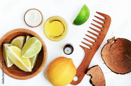 Healthy hair care beauty treatment ingredients, top view white table wooden natural haircomb, lemon citrus slices, fresh lime scent essential oil herbal extract in bowl