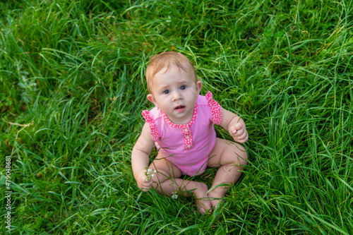 The child sits on the grass in summer. Selective focus.