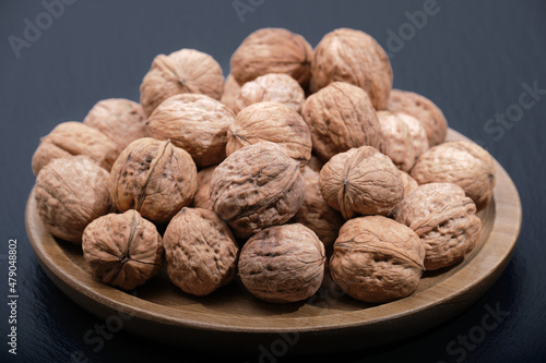 Group of walnuts on a black background. Nuts on a wooden plate close-up. Walnut on black copy space.
