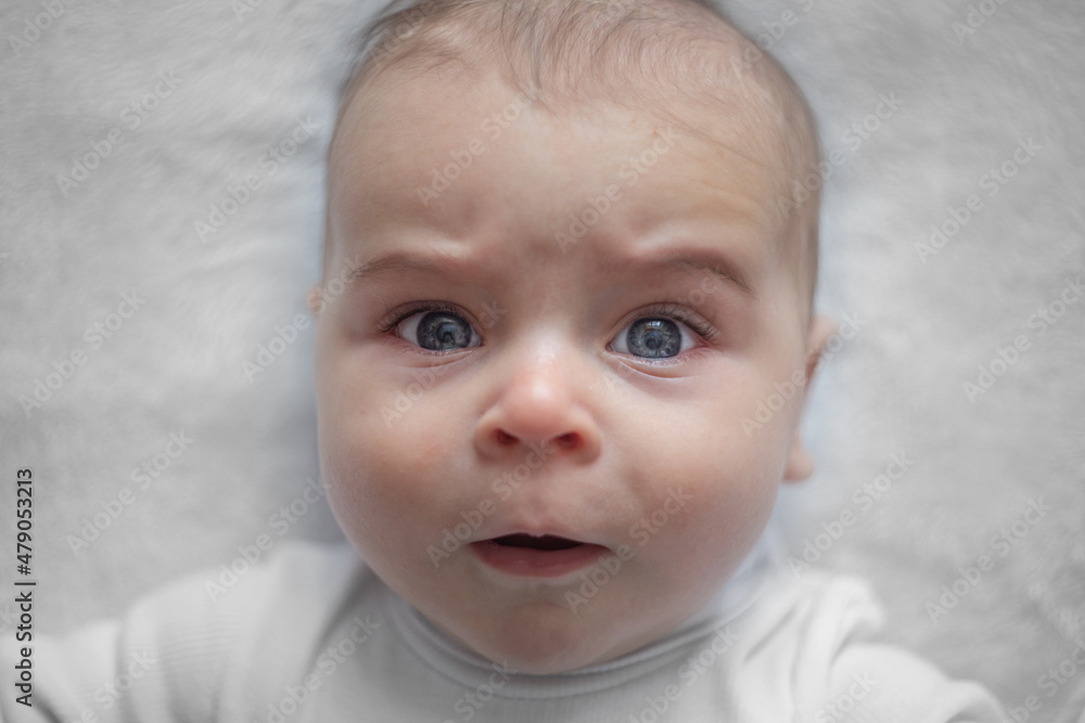 Surprised newborn baby. Portrait on a light background.