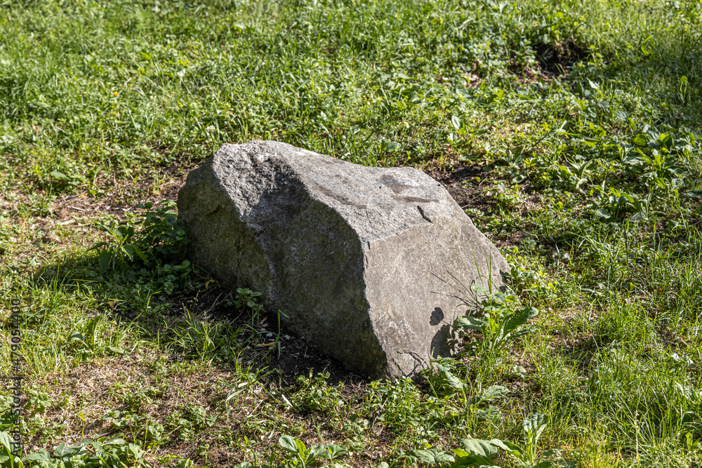 Big gray stone lies on green grass in the park in summer day Big gray stone lies on green grass in the park in summer day