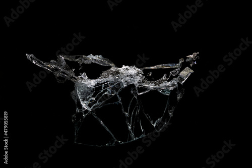 a crack on a broken glass mirror on a black background lines fragments bullet hole
