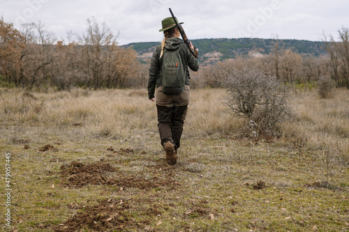 Hunter woman with shotgun hunting in the field.