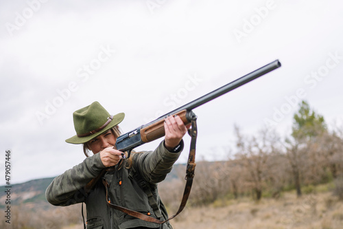 Hunter woman with shotgun hunting in the field. © karrastock