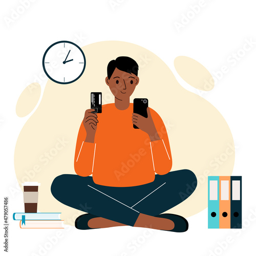 Online payment concept. The man sits cross-legged and holds a phone in one hand and a mobile in the other