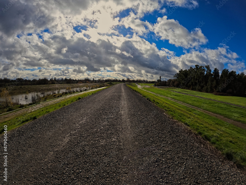 wide angle view of a levee gravel road on a cloudy day