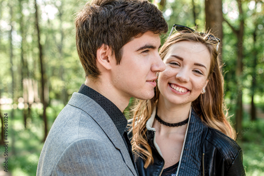 laughing happy girl in arms of loving guy. handsome young guy in park on a walk with a friend in spring. laughing happy girl in arms of loving guy. handsome young guy in park on a walk with a friend in spring.