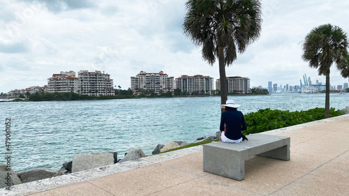 Woman sitting on the bench looking at the coast of Miami Beach.