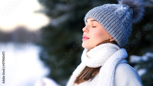 Side beauty portrait of beautiful attractive girl, young calm woman is breathing deep deeply fresh air at winter cold frosty snowy day with her eyes closed, meditating, doing breath exercise, enjoying
