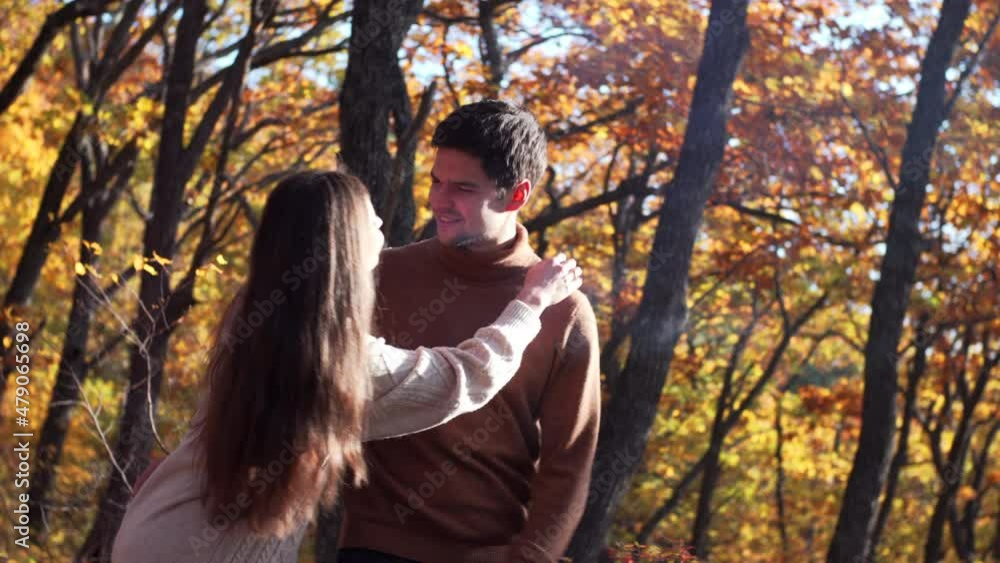 Couple in love. Woman closes her boyfriend eyes with her hands, they kiss each other and laugh. Beautiful park, yellow autumn trees on the background. Sunny day Couple in love. Woman closes her boyfriend eyes with her hands, they kiss each other and laugh. Beautiful park, yellow autumn trees on the background. Sunny day