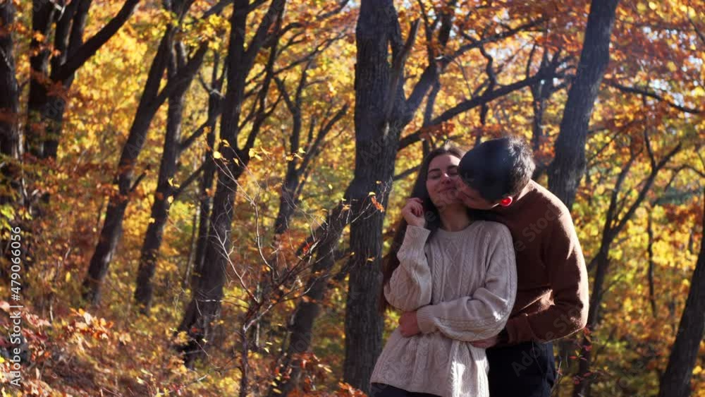 Caucasian couple in love. Woman and man are embracing, smiling and enjoying each other in the beautiful park, yellow autumn trees on the background. Wonderful sunny day Caucasian couple in love. Woman and man are embracing, smiling and enjoying each other in the beautiful park, yellow autumn trees on the background. Wonderful sunny day