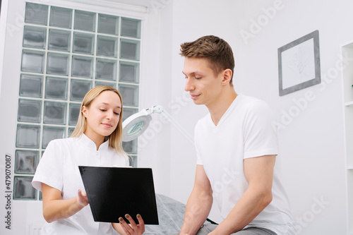Consultation in cosmetology clinic. Female professional beauty doctor talking with pretty young men.