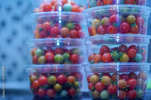 cherry tomatoes in container ready for sale with a blue blurred light effect in the background