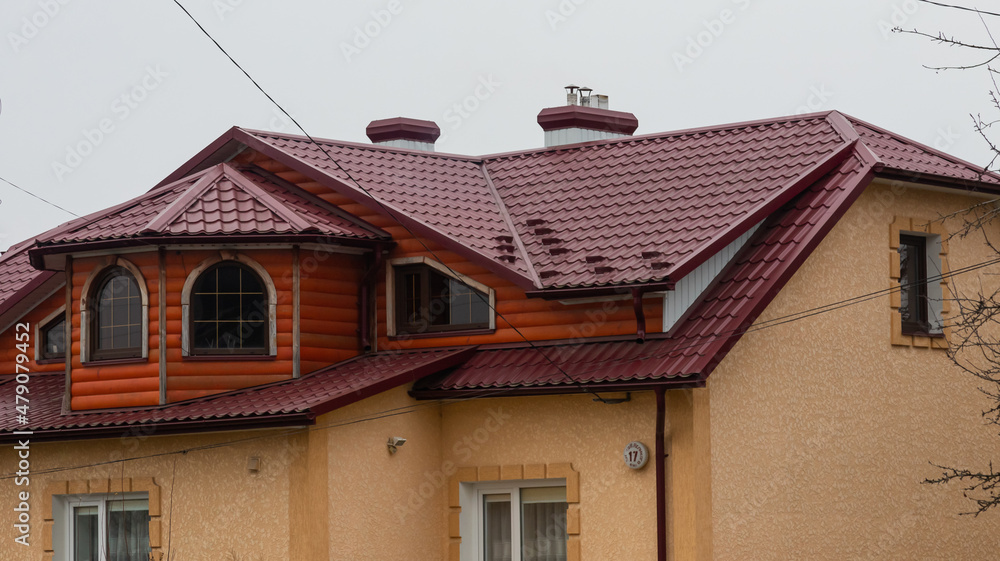 The roof of the house is made of red metal tiles, a beautiful large chimney