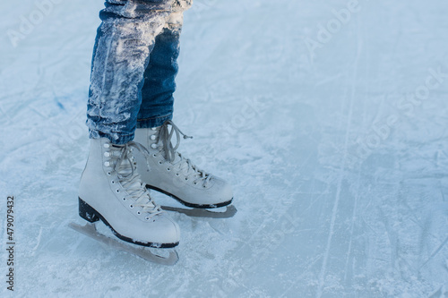 little girl in jeans in white figure skates on an outdoor ice rink, winter fun, outdoor ice rink