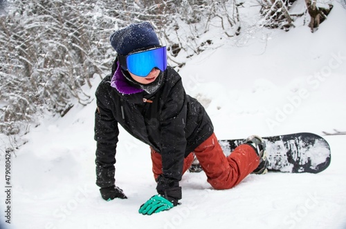 a girl with a snowboard sits on the side of the mountain