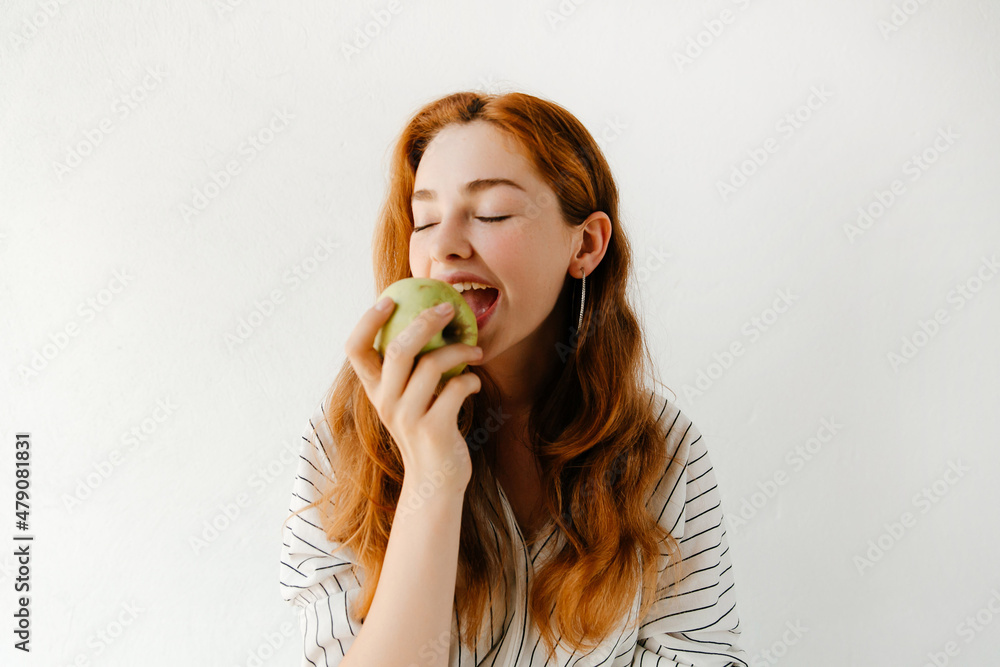 Close up portrait of beautiful young woman biting a green apple, having a snack after studying. Vegetarian food concept Close up portrait of beautiful young woman biting a green apple, having a snack after studying. Vegetarian food concept