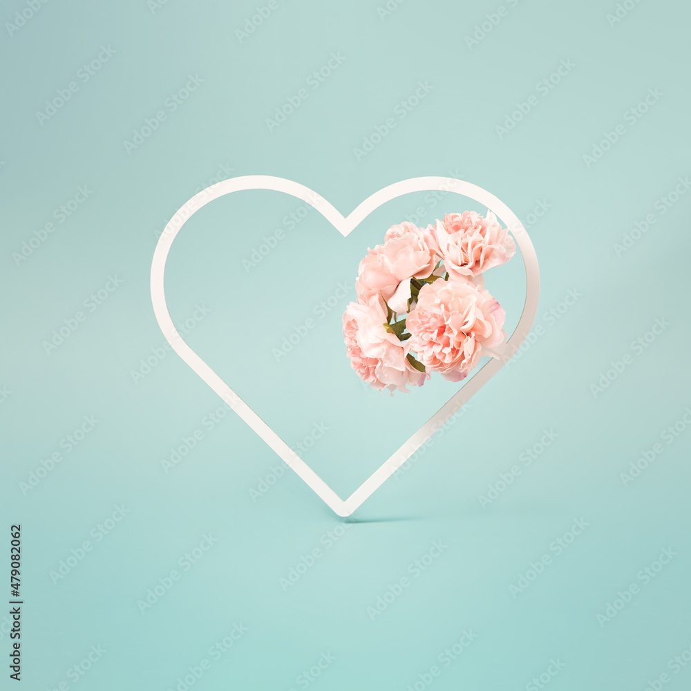 Pastel blue background with heart shaped frame with artificial flowers inside. Valentine's day minimal background.