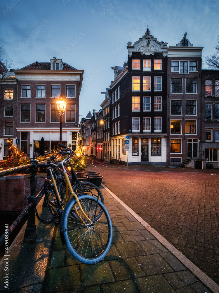 Bicycles, streetlights and illuminated historic canal houses along the Singel canal in Amsterdam