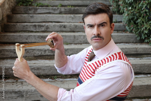 Valokuva Elegant man with a mustache holding vintage slingshot