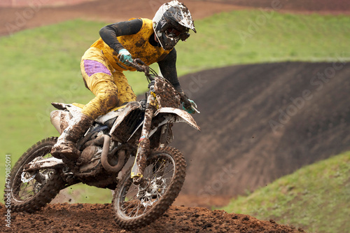 Motorcycle racer in the mud close-up racing on a dirt track. Selective focus.