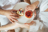 happy couple having breakfast in bed with delicious cookies with strawberries on top