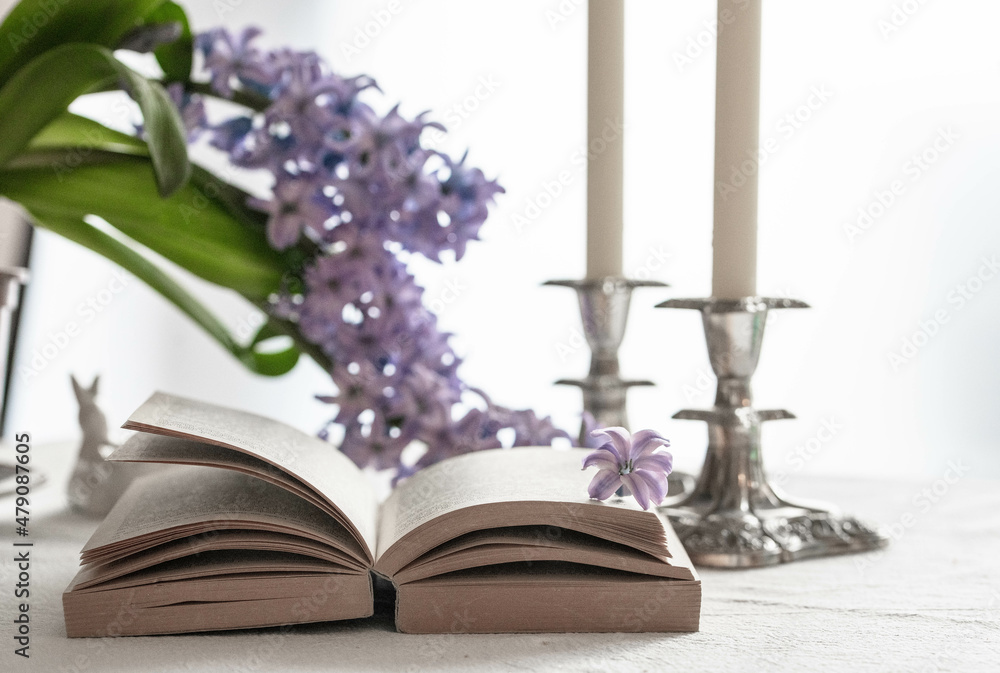open book and two candles on a table with spring flowers