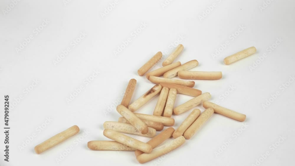 Freshly baked breadsticks, isolated on a white background. The girl throws a handful of breadsticks on the white table. Slow motion Freshly baked breadsticks, isolated on a white background. The girl throws a handful of breadsticks on the white table. Slow motion