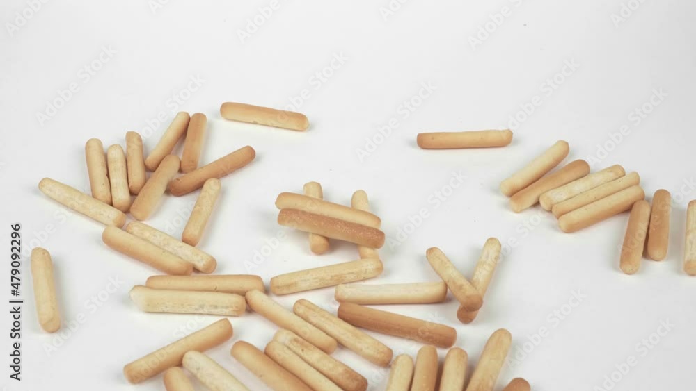 A handful of freshly baked breadsticks, isolated on a white background. The girl throws a handful of breadsticks on the white table. A handful of freshly baked breadsticks, isolated on a white background. The girl throws a handful of breadsticks on the white table.
