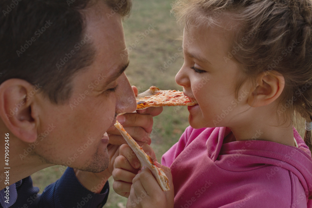 little girl and her dad feed each other pizza and laugh little girl and her dad feed each other pizza and laugh