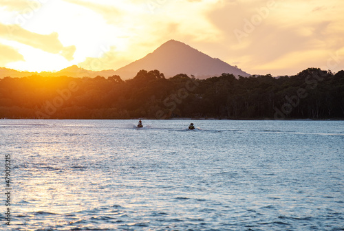 Two People Watching the Sunset from Jetski in a Seascape View Against Mountain.Vertical Image