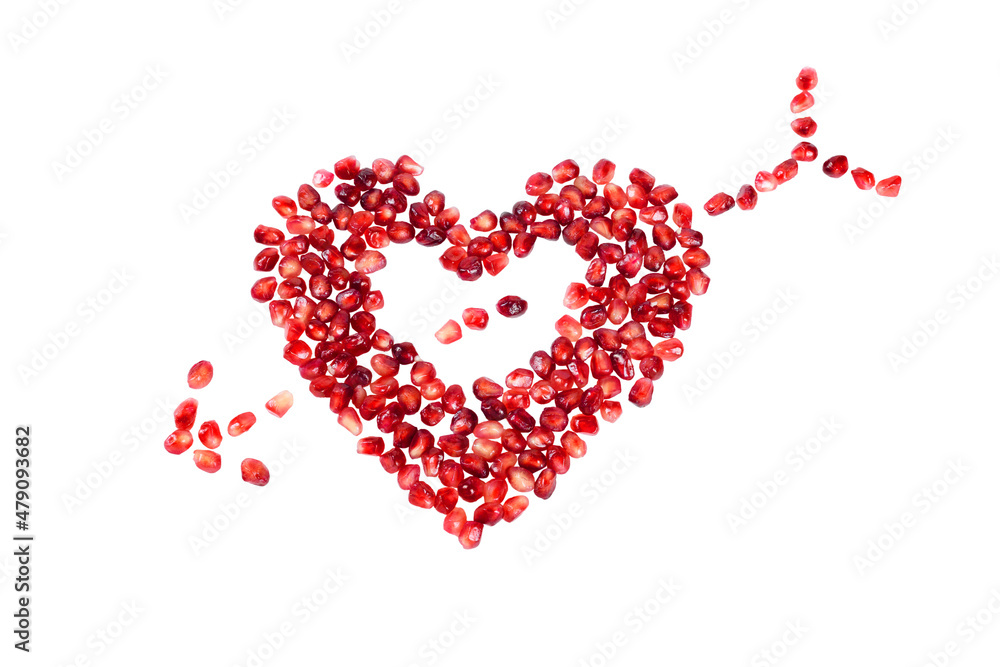 Ripe pomegranate kernels laid out in the form of a heart, isolated on a white background.