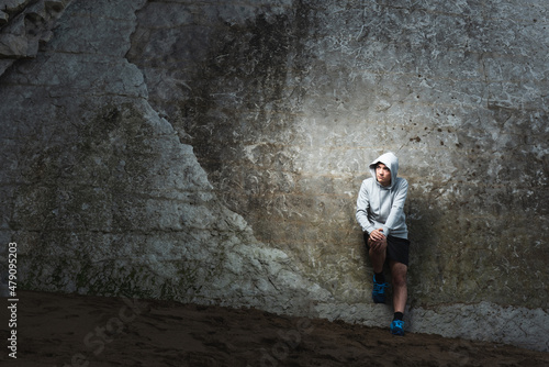 Serious thoughtful hispanic sportsman resting against a natural wall