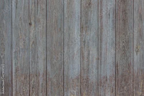 An old fence made of vertically assembled boards. Background, texture.