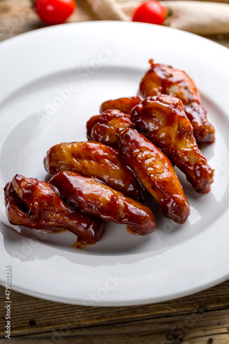 chicken wings in teriyaki sauce on white plate on wooden table