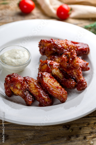 chicken wings in barbecue sauce on white plate on wooden table