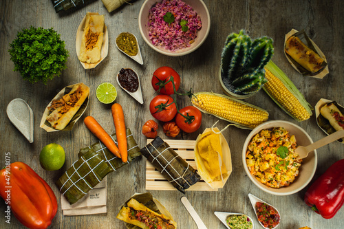 I LOVE FOOD SERIES. Latin American food on a wooden table with fresh, healthy and natural ingredients, such as corn, red pepper, hallacas, humita, tamale, carrot, tomato, lime, perfect for a dinner. photo